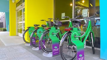 A row of green bicycles parked outside a building with a bright yellow exterior.