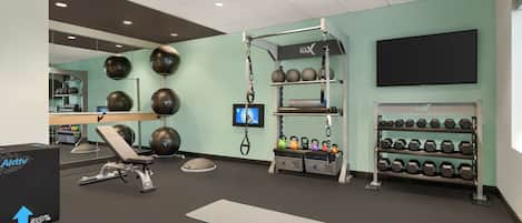 A gym with exercise equipment, a TV, and a mirror.
