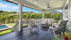 A covered outdoor area with a pool, lounge chairs, and a view of a tropical landscape. - Hale Lo'i + Cottage: 5BR home +pool in Sunny Poipu (Koloa)