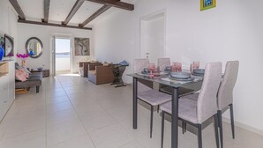Een eetruimte met een glazen tafel, grijs gestoffeerde stoelen en uitzicht op de omgeving.