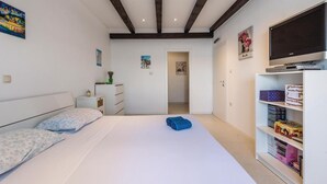 Een slaapkamer met een bed, een televisie en een boekenkast.