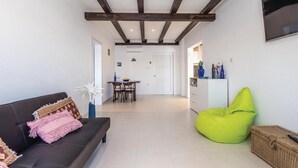 Een woonkamer met een donkere bank, een felgroene relaxfauteuil en een witte deur op de achtergrond.