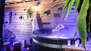 Un bain à remous dans une pièce en bois, avec un plafond, une chaise et une serviette.