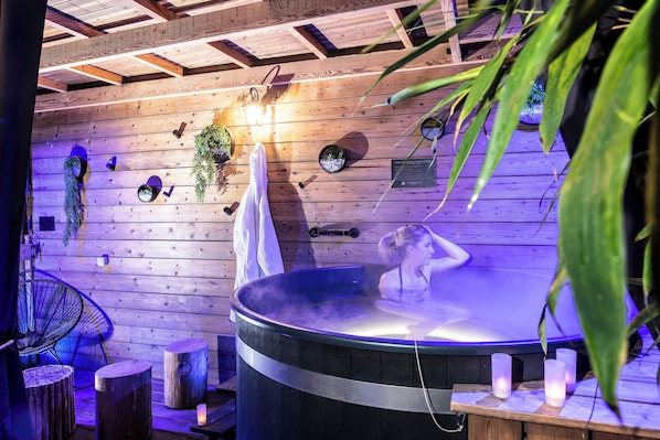 Un jacuzzi en una habitación de madera con techo, una silla y una toalla.