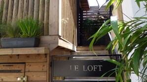 Une façade en bois avec une enseigne en métal noir portant l’inscription « LE LOFT ».