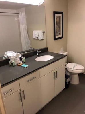A bathroom with a sink, mirror, and toilet. There are toiletries on the counter. - Harbor Steps (Seattle)