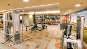 Un gimnasio con diversos equipos de ejercicio, incluyendo cintas de correr, máquinas de pesas y una bicicleta estática.