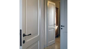 A hallway with white doors, one of which has a black handle. - Rinidia Siena Celso Cittadini Grande (Siena)