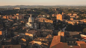 A densely packed urban area with historical architecture, including a prominent church with a dome and bell tower, surrounded by residential buildings with terracotta roofs. - Rinidia Siena Celso Cittadini Grande (Siena)