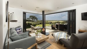 A modern living room with a sofa, coffee table, and a fireplace. - A stunning two bedroom eco-home with breath-taking countryside views. (Chapel Porth)