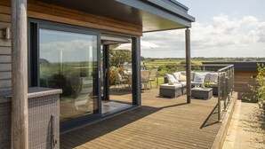 Eine moderne Außenterrasse mit Glastüren, die auf eine Patio mit Gartenmöbeln und Blick ins Grüne führt.