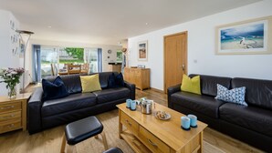 A modern living room with a sofa, coffee table, and dining area. - A superbly situated property that is just a short walk from two fabulous beaches (Newquay)