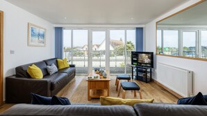 A modern living room with a sofa, a coffee table, and a TV. - A superbly situated property that is just a short walk from two fabulous beaches (Newquay)