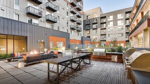 An outdoor patio with a long table, chairs, a barbecue grill, and a fire pit. - Bell Overlake (Redmond)