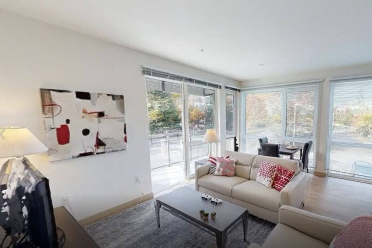 A modern living room with a sofa, coffee table, and a dining area with chairs.