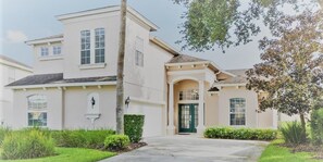 A two-story house with a front entrance, a covered porch, and a driveway. - ⭐️PREMIUM 5 Bed, 4 Bath Villa w/ private Pool, Only 15 mins to Disney gates!⭐️ (Davenport)