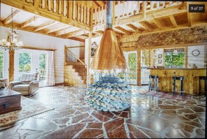 Experience the unique charm of this interior space, featuring a central stone structure, stone-tiled floor, and cozy seating areas.