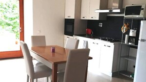 Une cuisine moderne avec des meubles blancs, une table à manger en bois et des chaises.