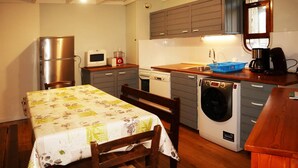 Une cuisine compacte équipée d’un réfrigérateur, d’un four à micro-ondes, d’une machine à café et d’un lave-linge.