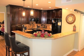 Kitchen features a central island with a marble countertop and stainless steel appliances.