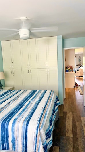 Une chambre à coucher avec un lit, un ventilateur de plafond et une armoire.