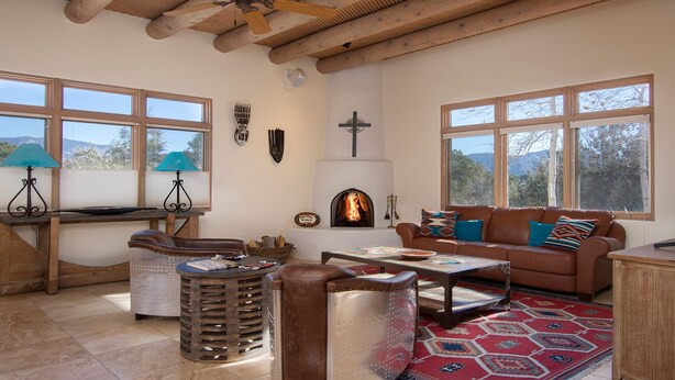 Un salon chaleureux avec une cheminée, des meubles en cuir et de grandes fenêtres donnant sur l’extérieur.