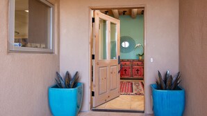 Un passage mène à une pièce dotée d’une porte en bois, d’un miroir au mur et d’une armoire rouge à deux tiroirs.