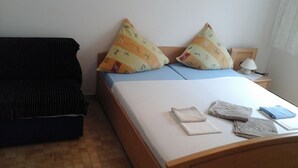 Un lit bien fait, avec des oreillers, une lampe de chevet et une petite table sur laquelle se trouve une autre lampe.