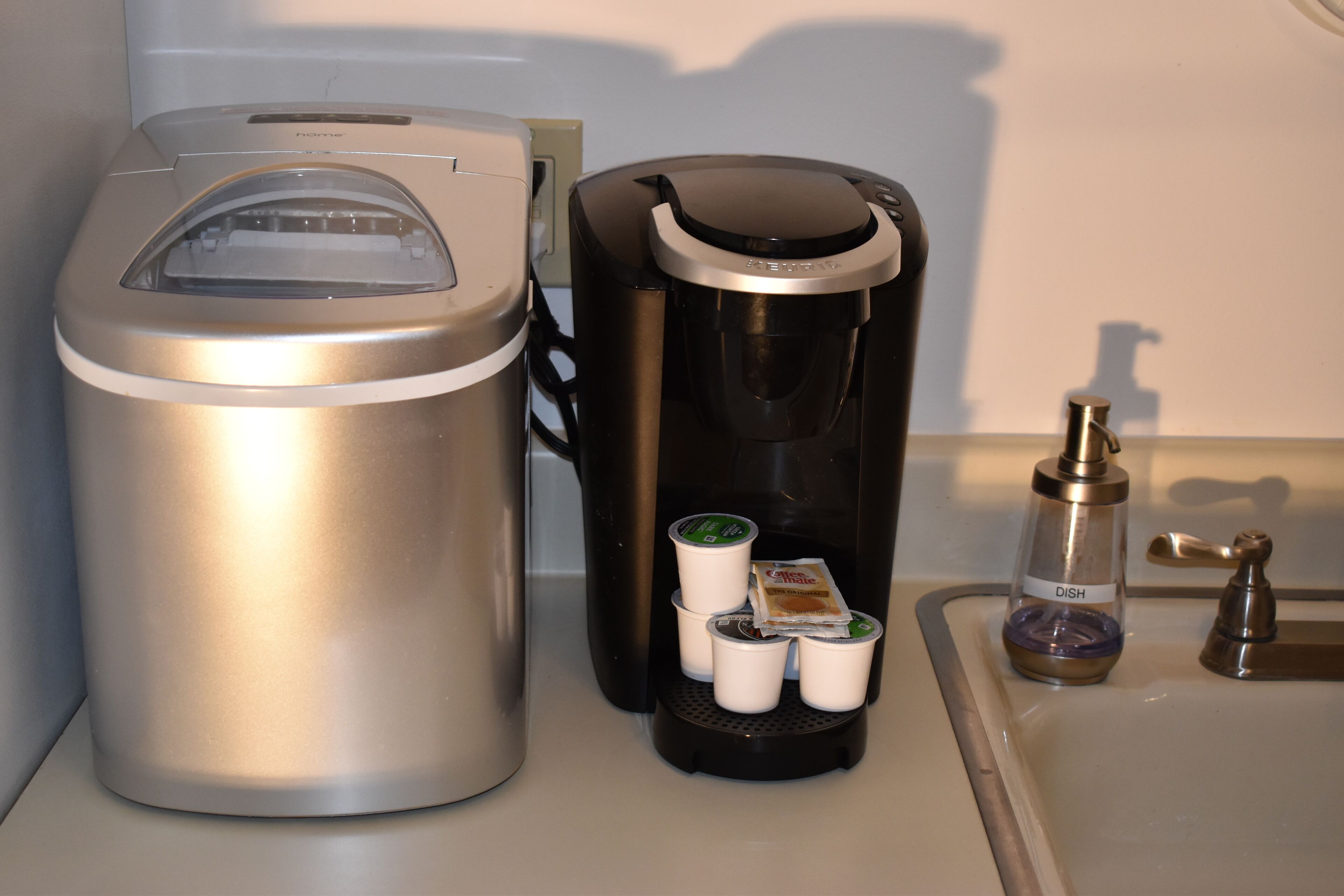 A coffee maker with a coffee pod dispenser and a trash can.