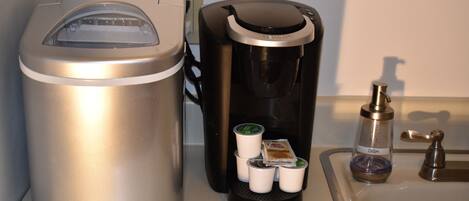 A coffee maker with a coffee pod dispenser and a trash can.