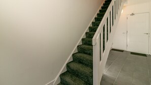 A staircase with carpeted steps and white railings, leading to a door. - Denby Lodge (Letchworth)