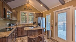 Una cocina con una isla grande, armarios de madera, un refrigerador de acero inoxidable y una ventana con persianas.