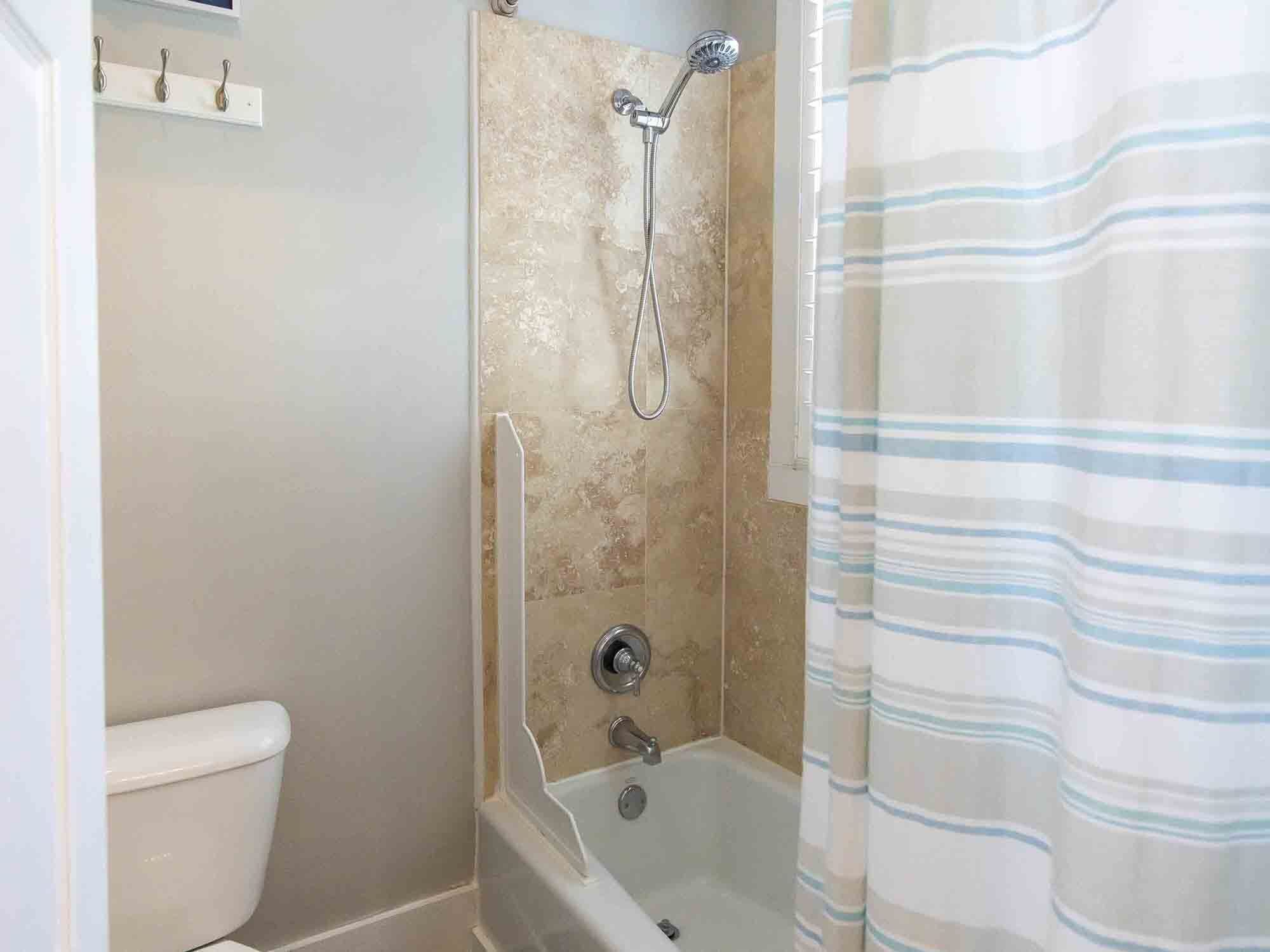 A bathroom with a shower, toilet, and a towel rack.