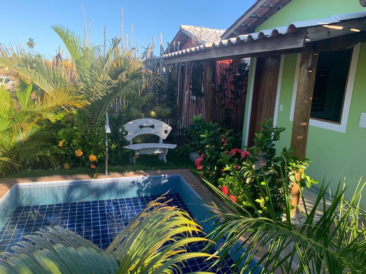 Una piscina rodeada de abundante vegetación y un banco de madera.