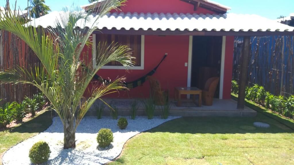 Ein rotes Haus mit weißem Dach, einer kleinen Veranda und einer Palme im Vorgarten.