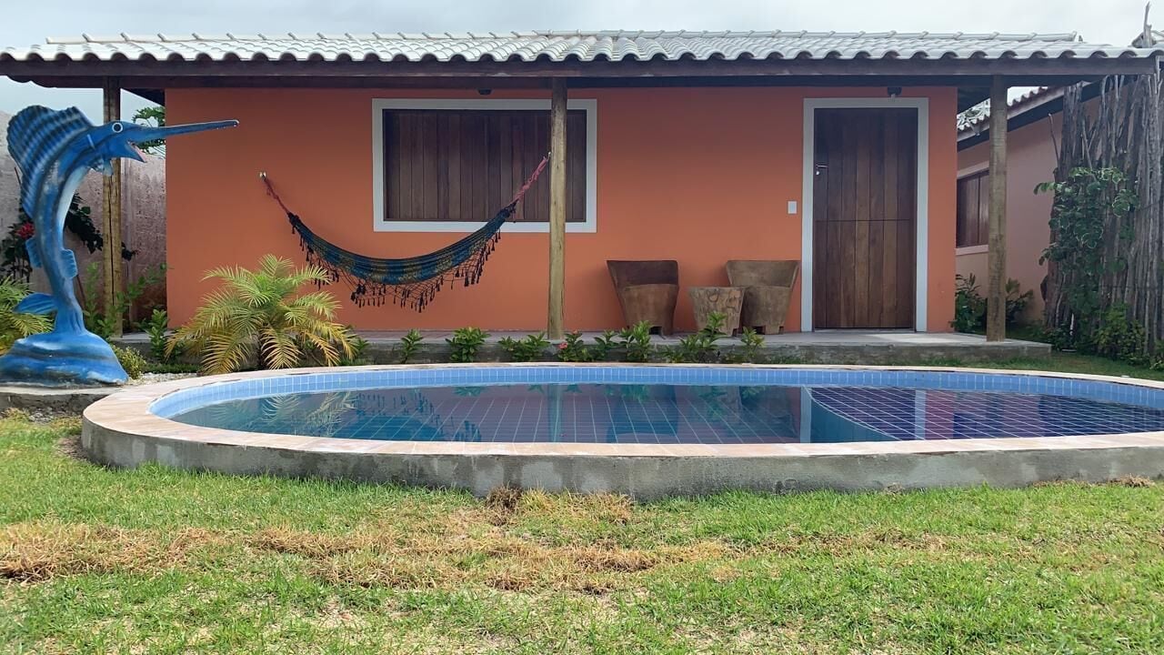 Een huis met een zwembad, een hangmat en een groot beeldhouwwerk.