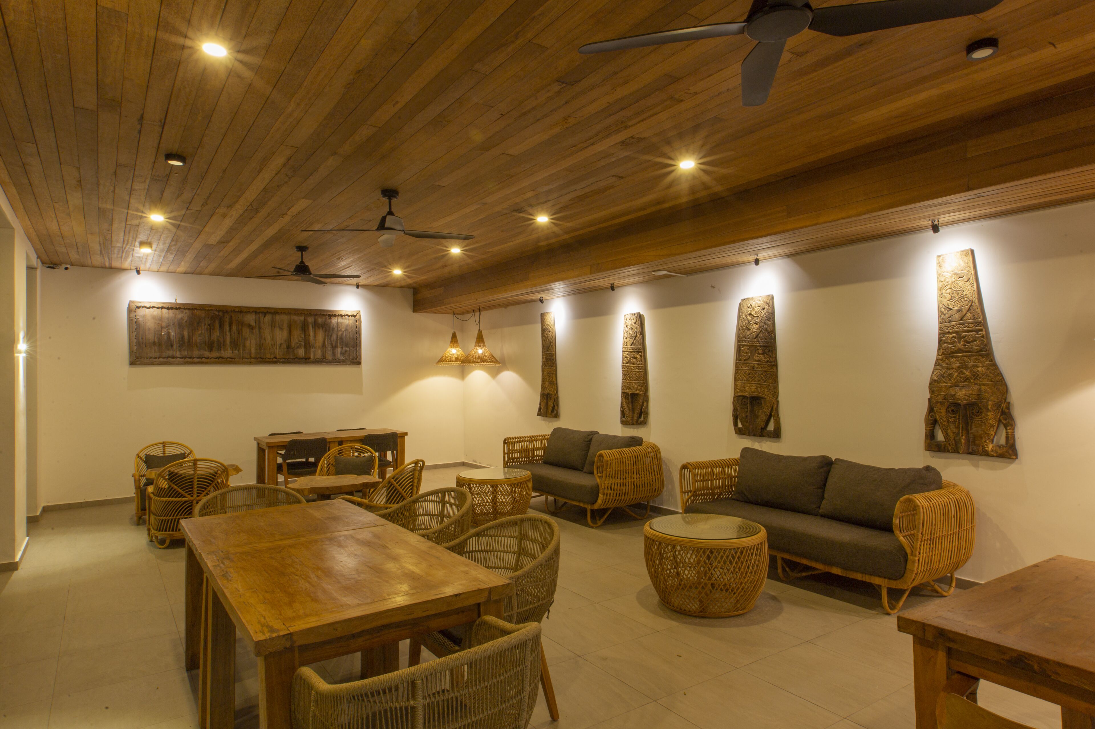 A spacious room with a wooden ceiling, wicker furniture, and wall-mounted decorative pieces.