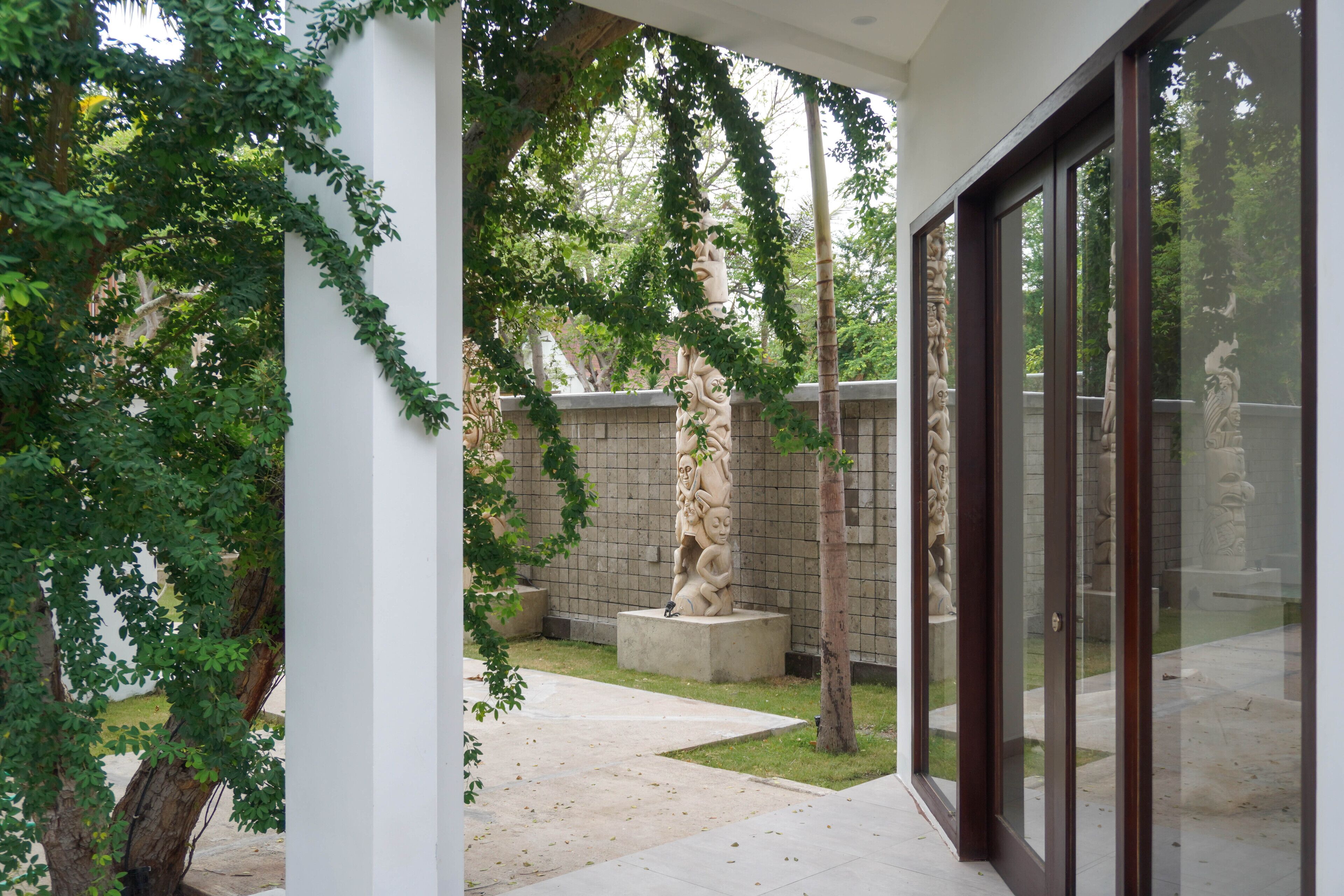 A courtyard with a statue, a brick wall, and a glass door leading to a room.