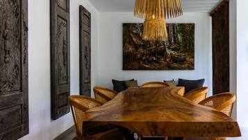 A dining area with a large wooden table, woven pendant light, and rustic decor.