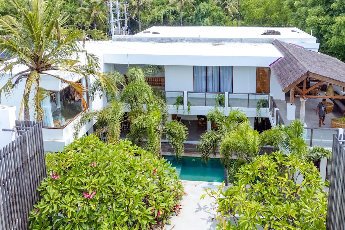 A modern house with a pool, surrounded by lush greenery and a wooden fence.