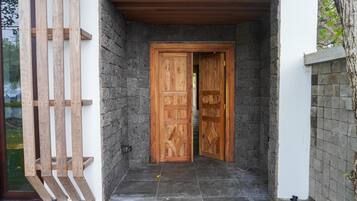 A wooden door with a geometric pattern, set in a stone wall entrance with a tiled floor.