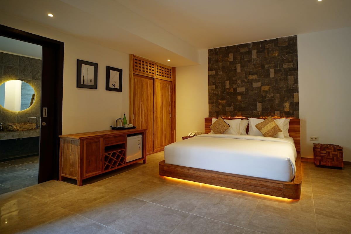 A bedroom with a large bed, wooden headboard, and a stone wall.