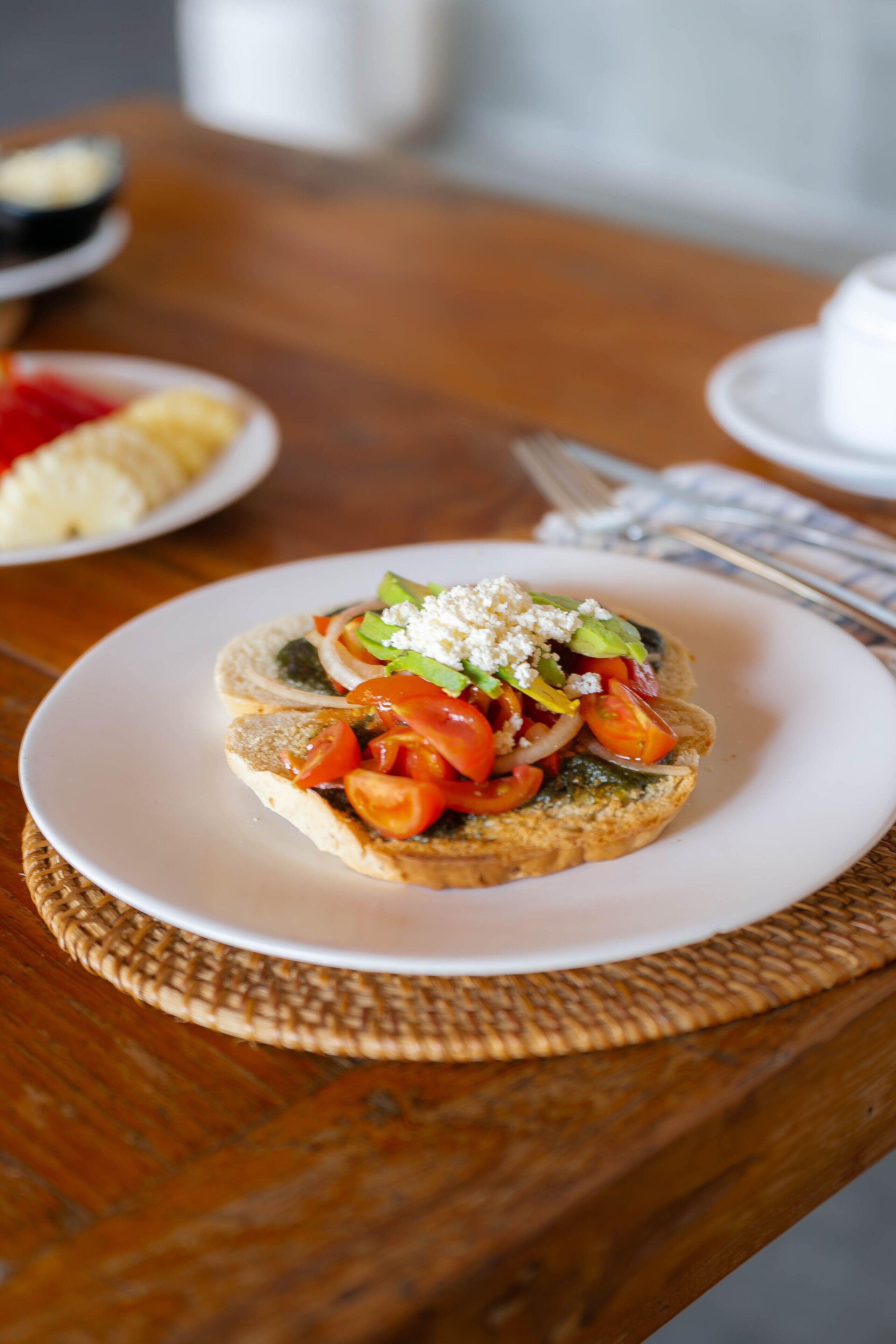 A plate with a sandwich on a white plate, placed on a wooden table.