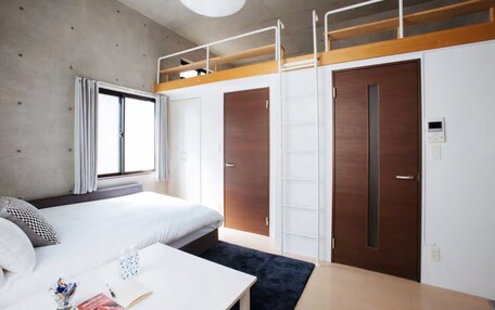 A modern hotel room with a bunk bed, a desk, and a wardrobe.