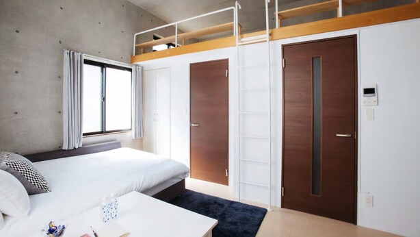 Et moderne hotelværelse med køjeseng, skrivebord og garderobeskab.