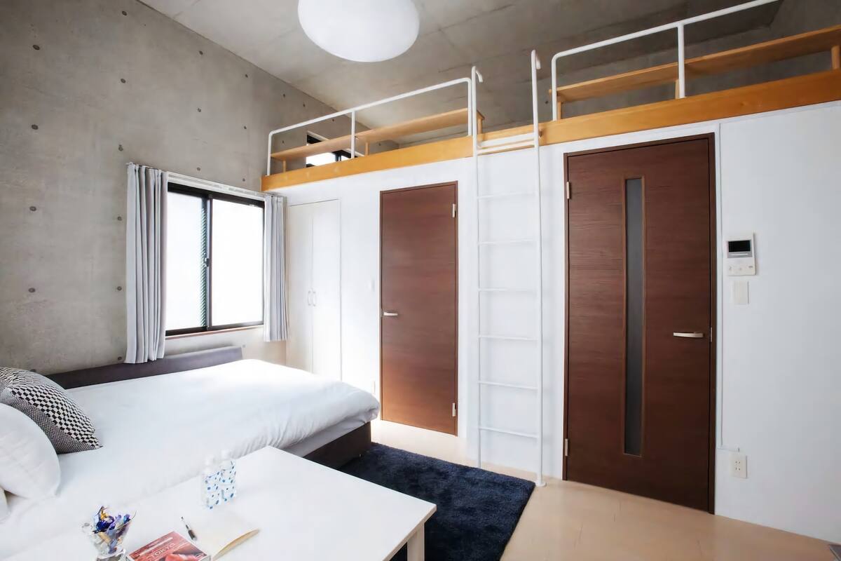 Ett modernt hotellrum med en våningssäng, ett skrivbord och en garderob.