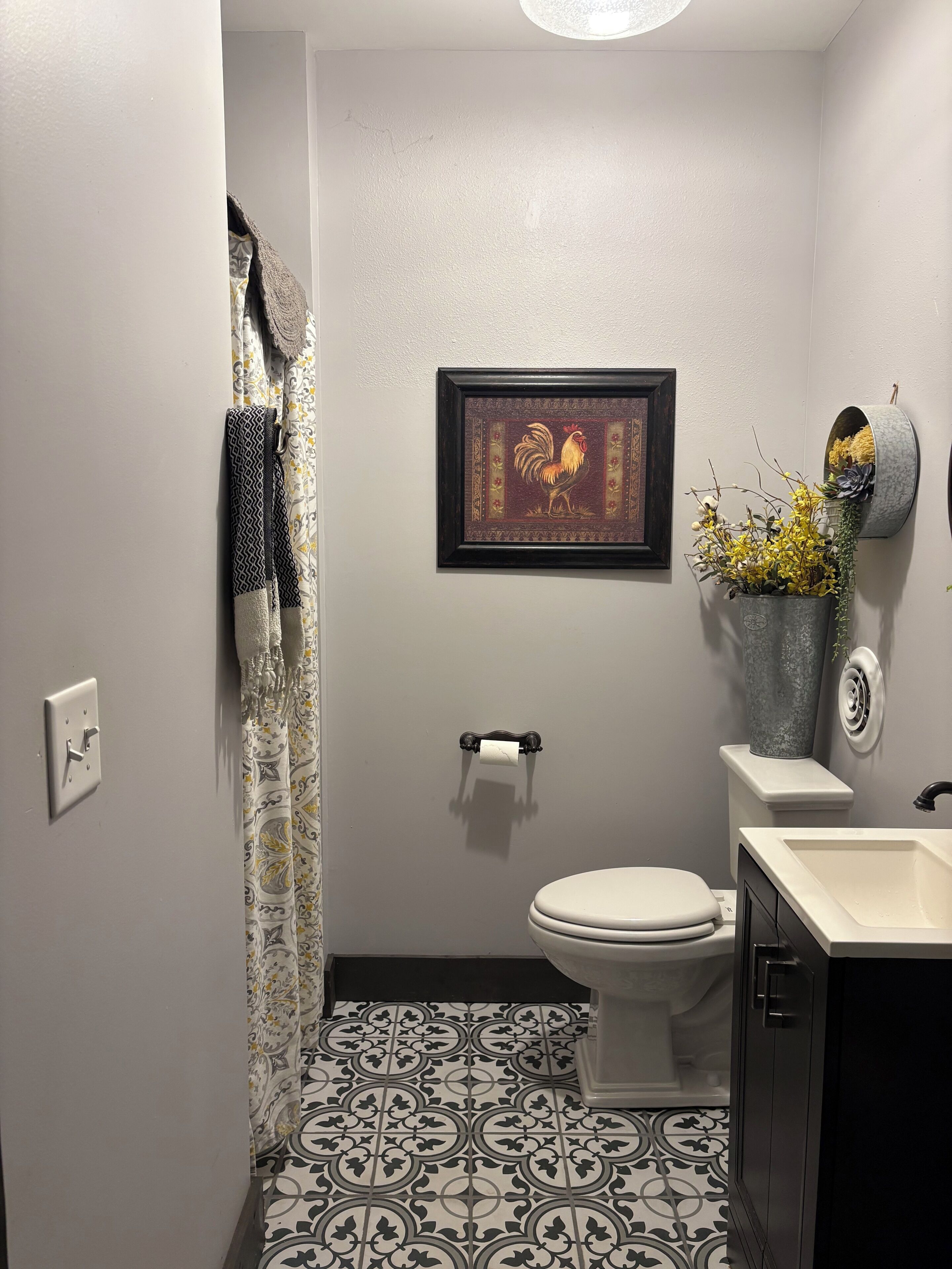 Une salle de bain avec des toilettes, un lavabo, un tableau encadré et une plante en pot.