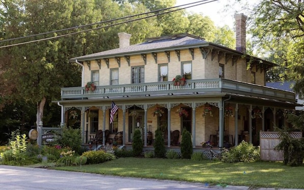 A two-story house with a porch, a chimney, and a flag.