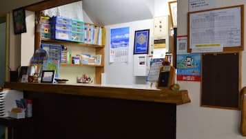 A reception desk with a wooden counter, various office supplies, a calendar, and a PayPay payment terminal.