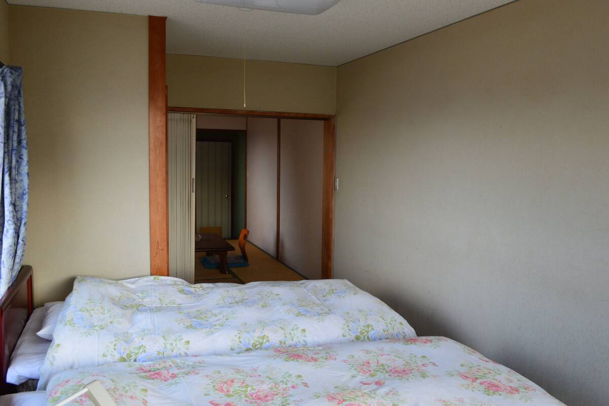 Une pièce comprenant un lit, une armoire en bois, une petite table et une chaise.